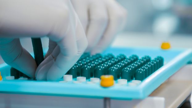 Sodium Bicar (API) Close-up of gloved hands working with capsules in a pharmaceutical lab setting.