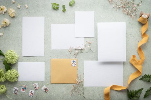 A sophisticated flat lay of blank papers, an envelope, and floral accents for creative stationery mockups.