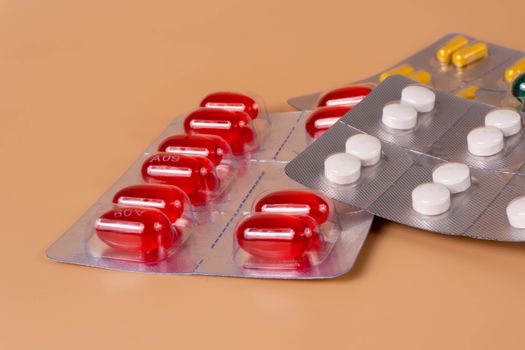 Various pills and capsules in blister packs on a solid orange background.