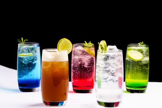 Vibrant mixed cocktails with lime and mint garnishes, set against a black background.