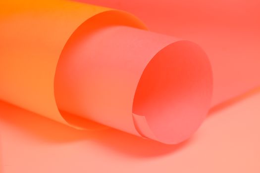 Close-up of rolled pink and orange paper creating a vibrant abstract background.