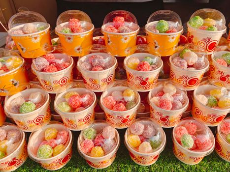 A vibrant array of sugar-coated jelly candies in decorative cups, displayed outdoors in Manila.