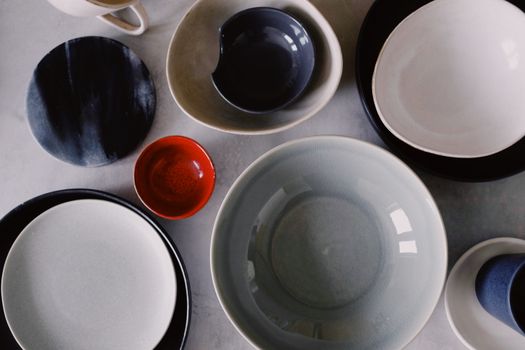 A collection of various colored ceramic bowls and plates, artistically arranged on a flat surface.