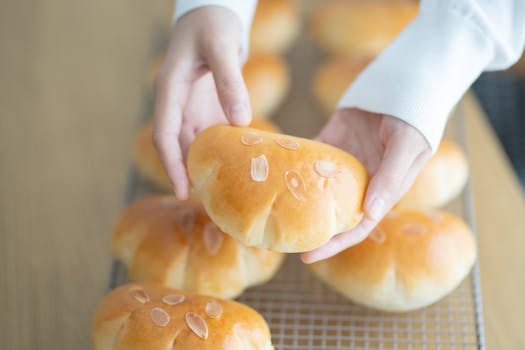 Sodium Bicar Hands holding freshly baked bread with almonds on top, perfect for bakery or culinary theme.