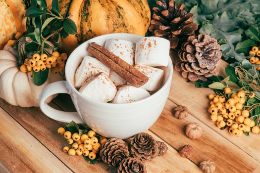 A warm rustic display featuring marshmallows, cinnamon, pumpkins, and autumn foliage, perfect for fall themes.