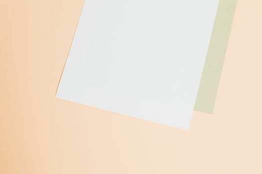 Two sheets of blank paper on a soft pastel background with room for text or design.