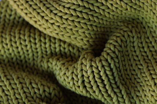 Detailed close-up of a green knitted fabric, showcasing its textured pattern.