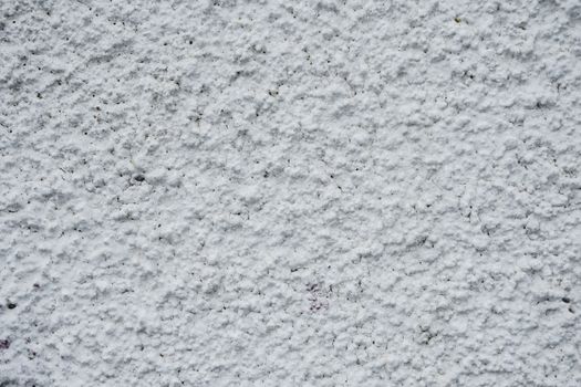 Textured white wall of old concrete building on street of town in daytime