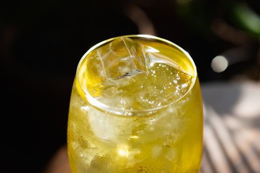 Close-up of a chilled yellow drink with ice cubes in a glass, perfect for a refreshing moment.