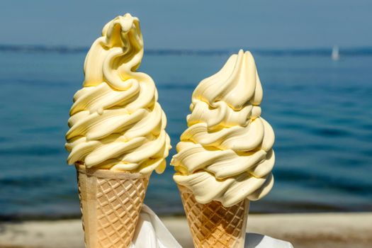 Delicious vanilla ice cream cones enjoyed seaside, perfect for a sunny day treat.