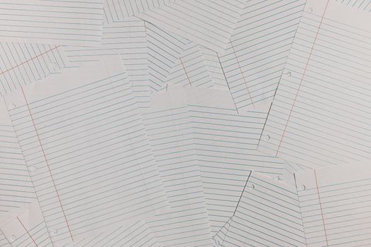 Overhead view of scattered blank lined paper sheets creating a textured background.
